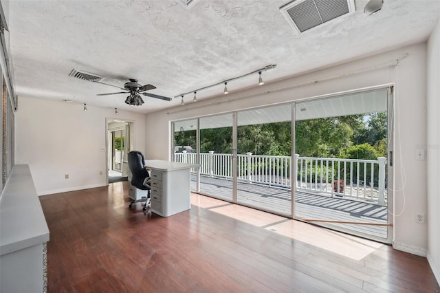 unfurnished office with visible vents, a textured ceiling, dark wood-type flooring, and a ceiling fan