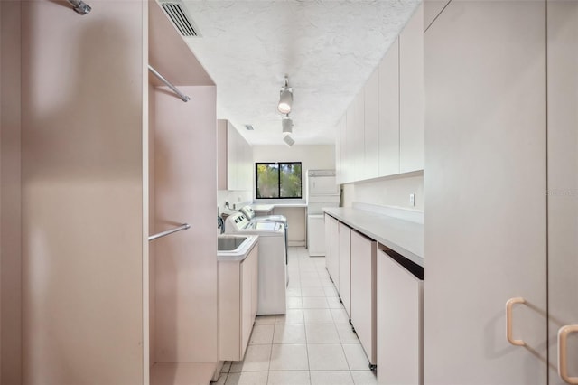 kitchen featuring washing machine and dryer, light tile patterned flooring, a textured ceiling, stainless steel fridge, and white cabinets