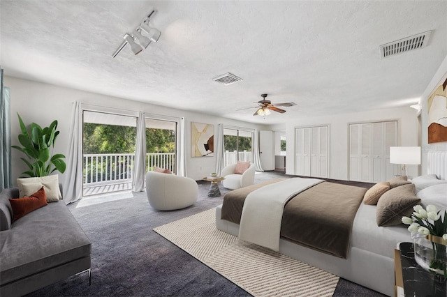 carpeted bedroom featuring multiple closets, a textured ceiling, access to exterior, and ceiling fan