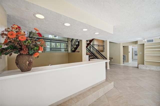 hall featuring tile patterned floors, visible vents, a textured ceiling, recessed lighting, and stairway