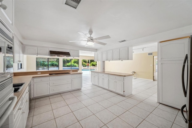 kitchen with appliances with stainless steel finishes, light tile patterned flooring, kitchen peninsula, ceiling fan, and white cabinets