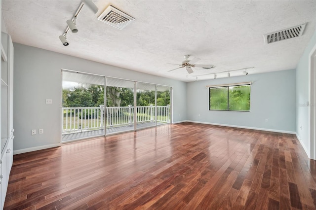 spare room with dark hardwood / wood-style flooring, a textured ceiling, ceiling fan, and rail lighting