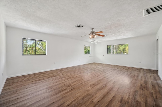 unfurnished room featuring ceiling fan, wood finished floors, visible vents, and a textured ceiling