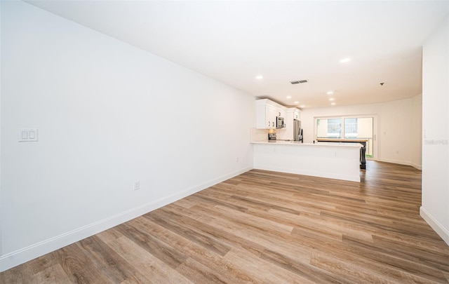 unfurnished living room featuring light wood-type flooring, visible vents, baseboards, and recessed lighting