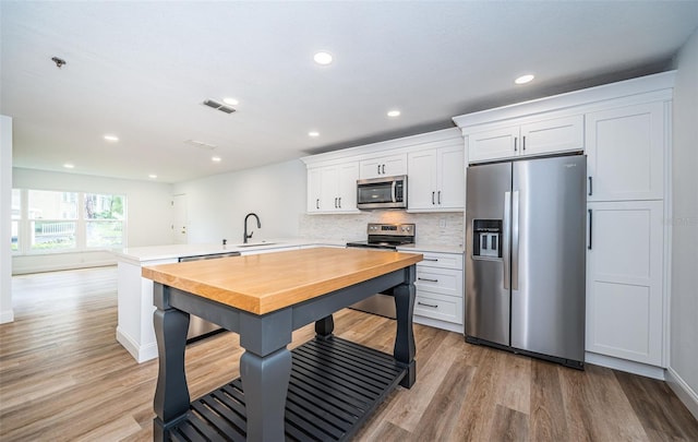 kitchen featuring stainless steel appliances, white cabinets, light countertops, and a peninsula