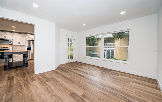 unfurnished living room featuring light wood-style floors, baseboards, and recessed lighting