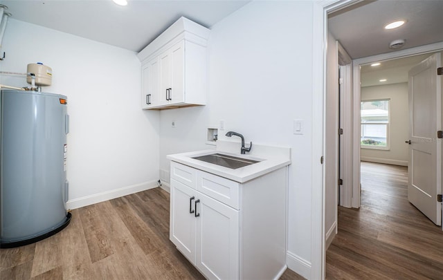 laundry room featuring water heater, washer hookup, wood-type flooring, sink, and hookup for an electric dryer