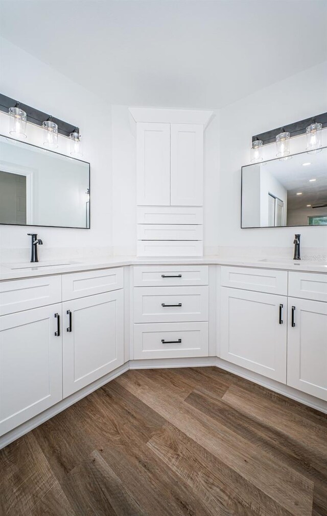 full bathroom featuring double vanity, a sink, and wood finished floors