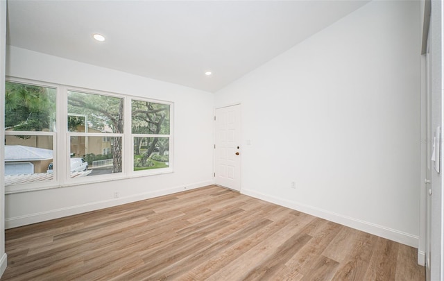 spare room with lofted ceiling and light hardwood / wood-style floors