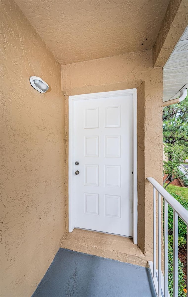 doorway to property with a balcony and stucco siding