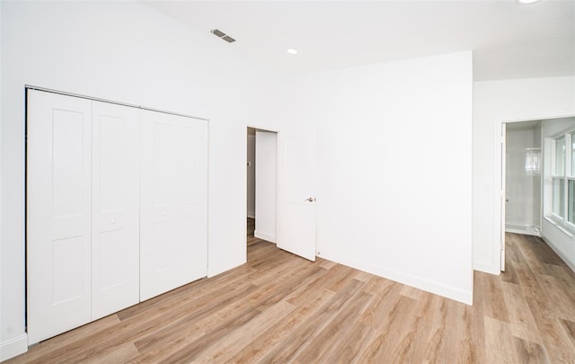 unfurnished bedroom featuring a closet, visible vents, baseboards, and light wood finished floors