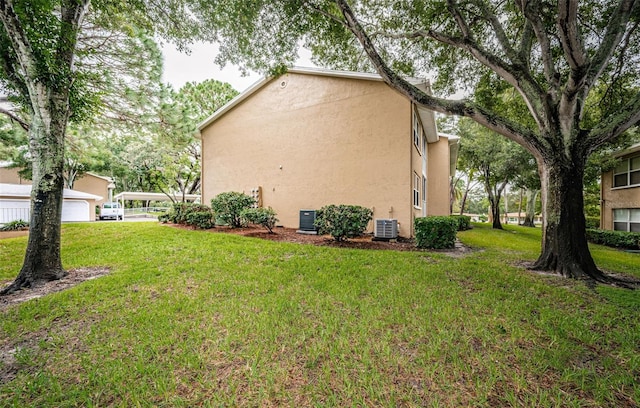 view of side of home featuring a lawn, a garage, and central AC unit