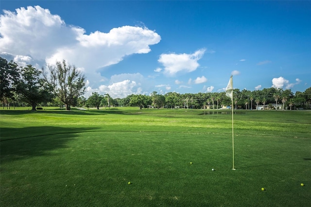 view of property's community featuring view of golf course and a lawn