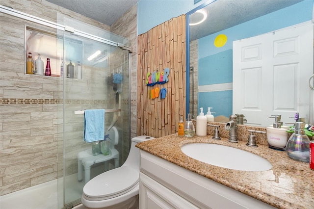 bathroom featuring a textured ceiling, vanity, toilet, and a shower with door