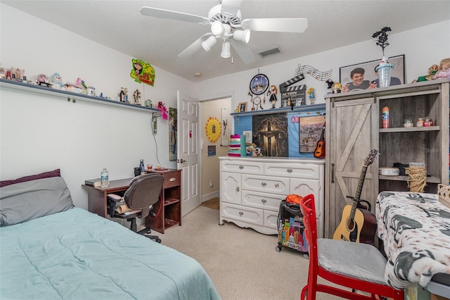 bedroom with ceiling fan, light carpet, and a barn door