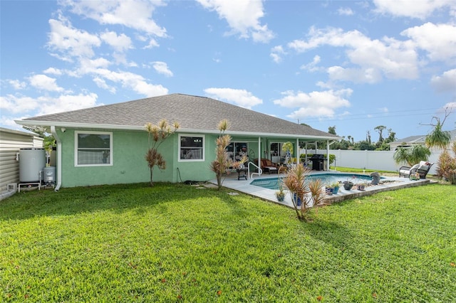 rear view of house featuring a patio, a yard, and a fenced in pool