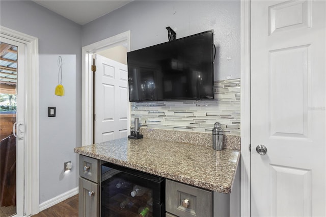 bar with beverage cooler, stone counters, dark wood-type flooring, and decorative backsplash