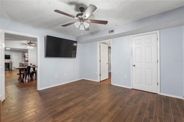 interior space with ceiling fan, dark hardwood / wood-style flooring, and a textured ceiling