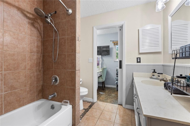 full bathroom featuring vanity, tiled shower / bath combo, tile patterned flooring, toilet, and a textured ceiling