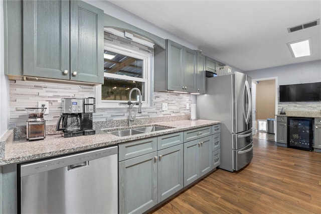 kitchen featuring wine cooler, sink, tasteful backsplash, dark wood-type flooring, and appliances with stainless steel finishes