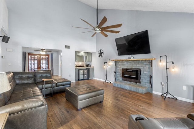 living room featuring a fireplace, high vaulted ceiling, hardwood / wood-style floors, and ceiling fan