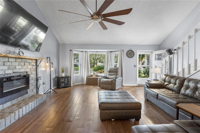 living room with ceiling fan, vaulted ceiling, dark hardwood / wood-style flooring, and a textured ceiling