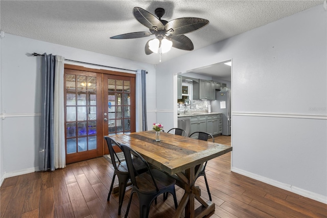 dining area featuring ceiling fan, sink, french doors, a textured ceiling, and dark hardwood / wood-style floors