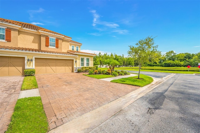 mediterranean / spanish-style home featuring a garage and a front lawn