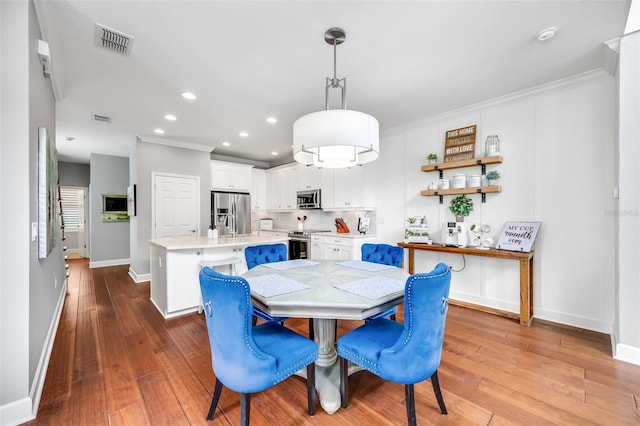 dining area featuring crown molding and hardwood / wood-style flooring