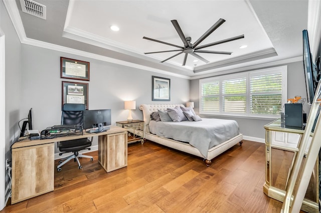 bedroom with a tray ceiling, hardwood / wood-style flooring, ornamental molding, and ceiling fan