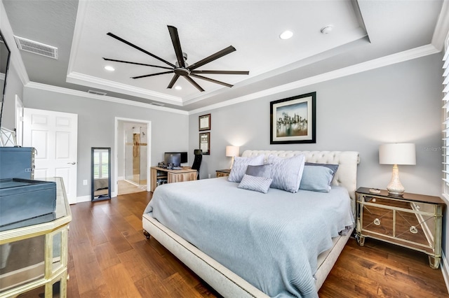 bedroom with ceiling fan, a raised ceiling, dark hardwood / wood-style flooring, and crown molding