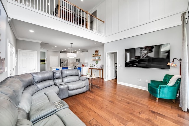 living room with crown molding, a towering ceiling, and wood-type flooring