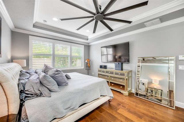 bedroom with a tray ceiling, ceiling fan, hardwood / wood-style flooring, and crown molding