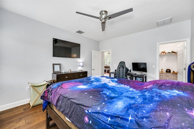 bedroom with a closet, a walk in closet, ceiling fan, and dark hardwood / wood-style floors