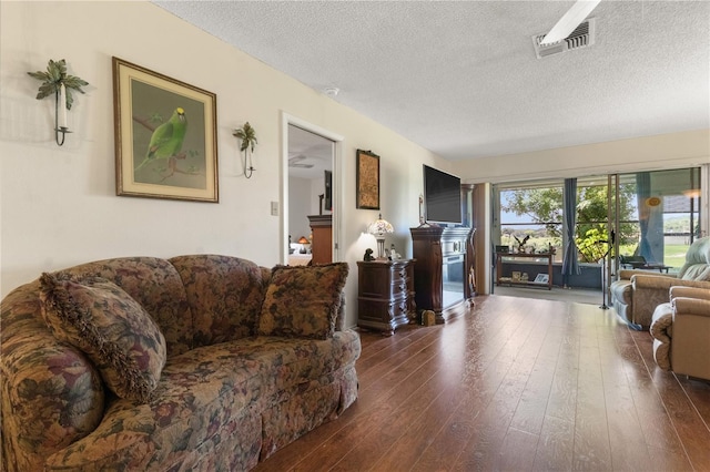 living room with a textured ceiling and dark hardwood / wood-style floors