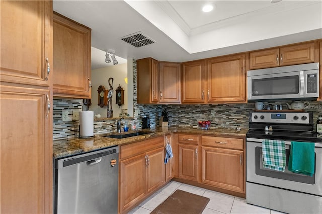 kitchen featuring appliances with stainless steel finishes, decorative backsplash, dark stone countertops, and sink