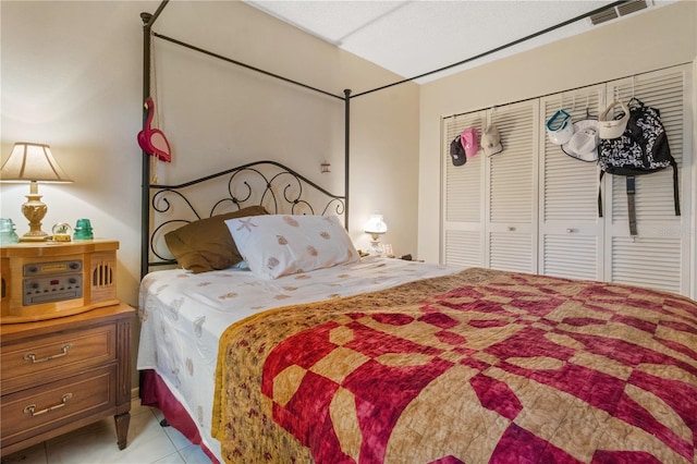 tiled bedroom with a closet and visible vents