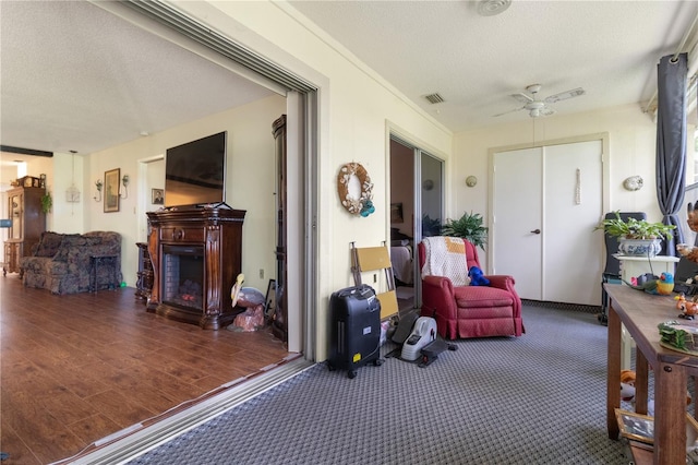 exterior space with a warm lit fireplace, visible vents, and ceiling fan