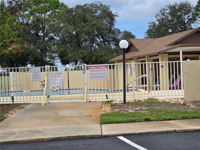 exterior space with a shingled roof, fence, and a gate