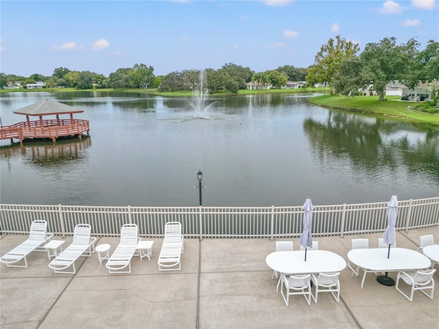 view of patio featuring a water view and fence