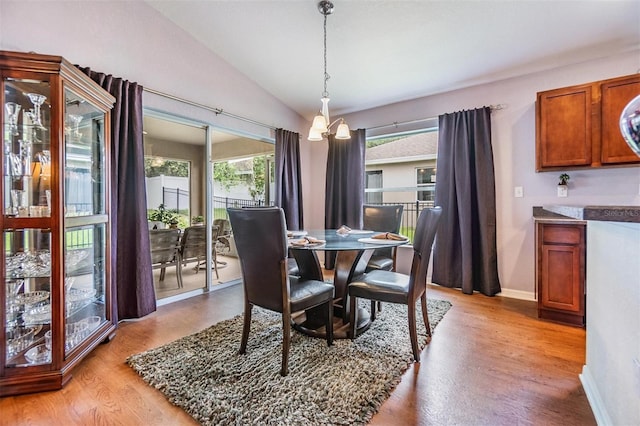 dining space with lofted ceiling, an inviting chandelier, and light hardwood / wood-style floors