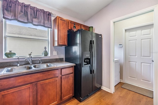 kitchen featuring light hardwood / wood-style flooring, washer / clothes dryer, sink, lofted ceiling, and black fridge