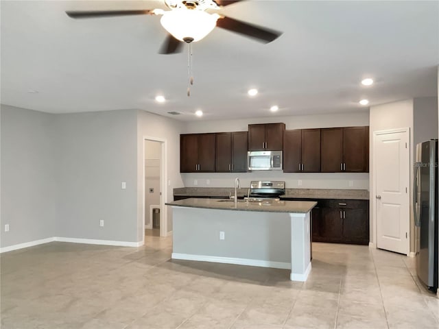 kitchen featuring appliances with stainless steel finishes, a kitchen island with sink, sink, ceiling fan, and dark brown cabinetry