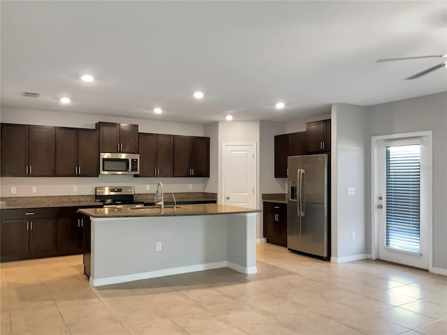 kitchen with dark brown cabinetry, stainless steel appliances, sink, and a center island with sink