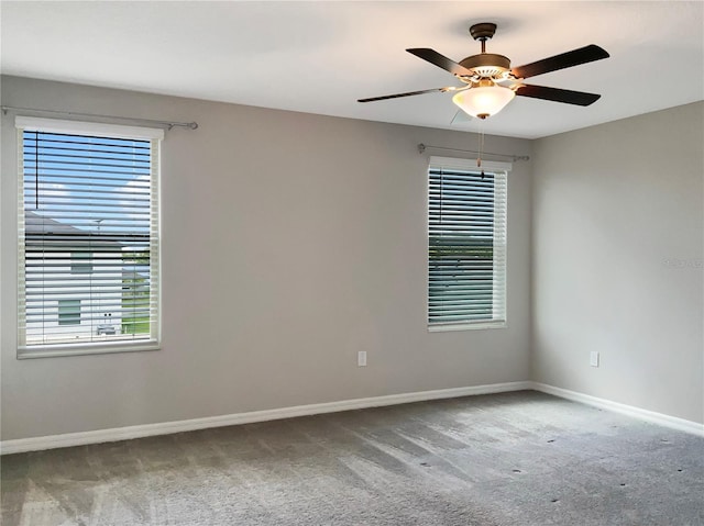 carpeted spare room featuring a healthy amount of sunlight and ceiling fan