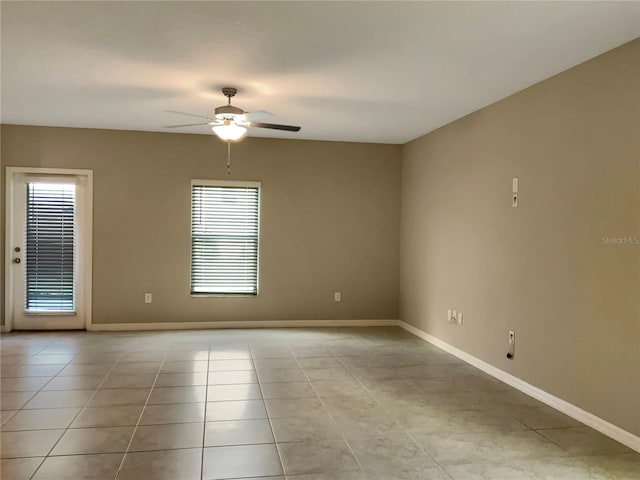 empty room with ceiling fan, light tile patterned floors, and a healthy amount of sunlight