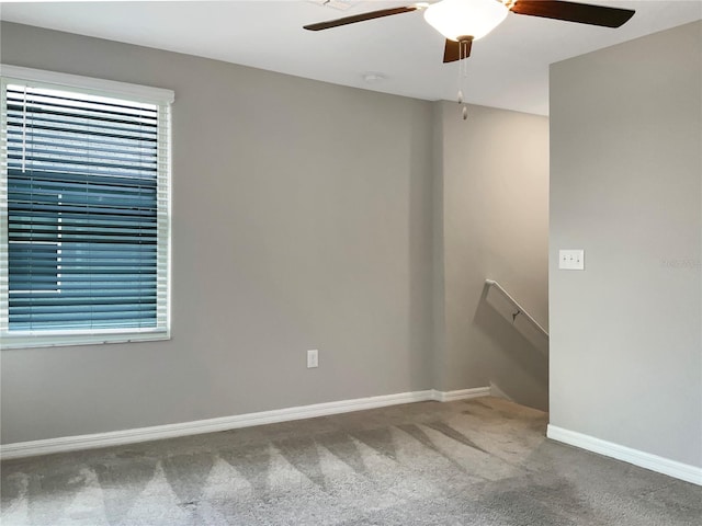 empty room with a wealth of natural light, ceiling fan, and carpet floors