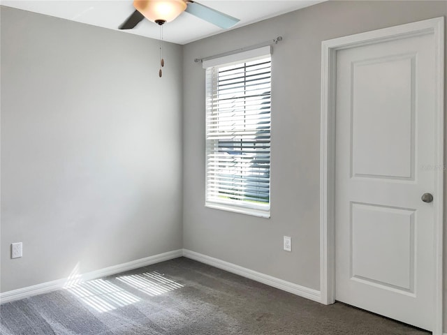 spare room featuring a wealth of natural light, dark carpet, and ceiling fan