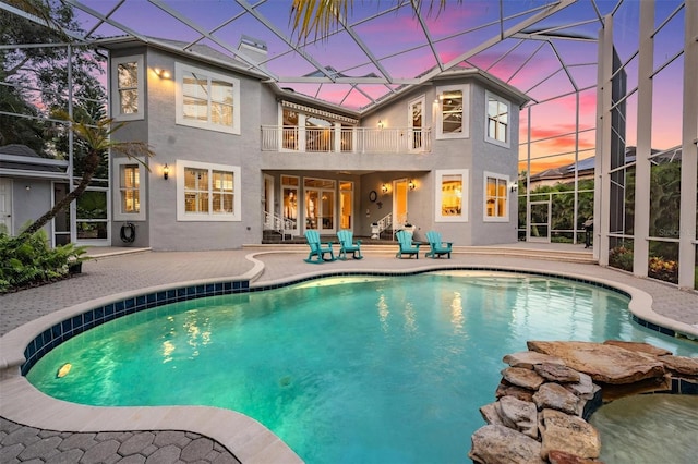 pool at dusk featuring a patio area and a lanai