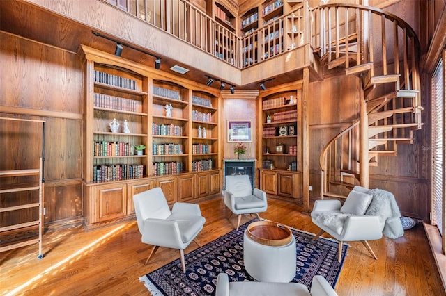 living area with hardwood / wood-style flooring, built in features, wood walls, and a towering ceiling